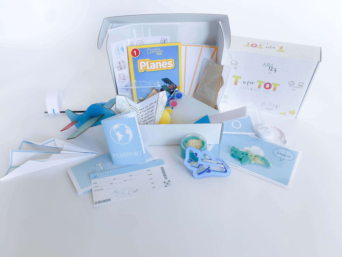 Airplane play and learn kit for kids, featuring supplies to construct and create four different airplanes, including a paper airplane, wooden airplane, straw airplane, and constructed airplane. Comes with homemade playdough, airplane playdough cutter, measuring tape, airplane tickets, passport, and a children's plane book for imaginative play and learning.
