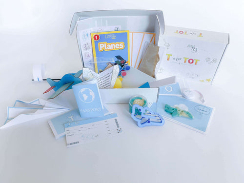 Airplane play and learn kit for kids, featuring supplies to construct and create four different airplanes, including a paper airplane, wooden airplane, straw airplane, and constructed airplane. Comes with homemade playdough, airplane playdough cutter, measuring tape, airplane tickets, passport, and a children's plane book for imaginative play and learning.