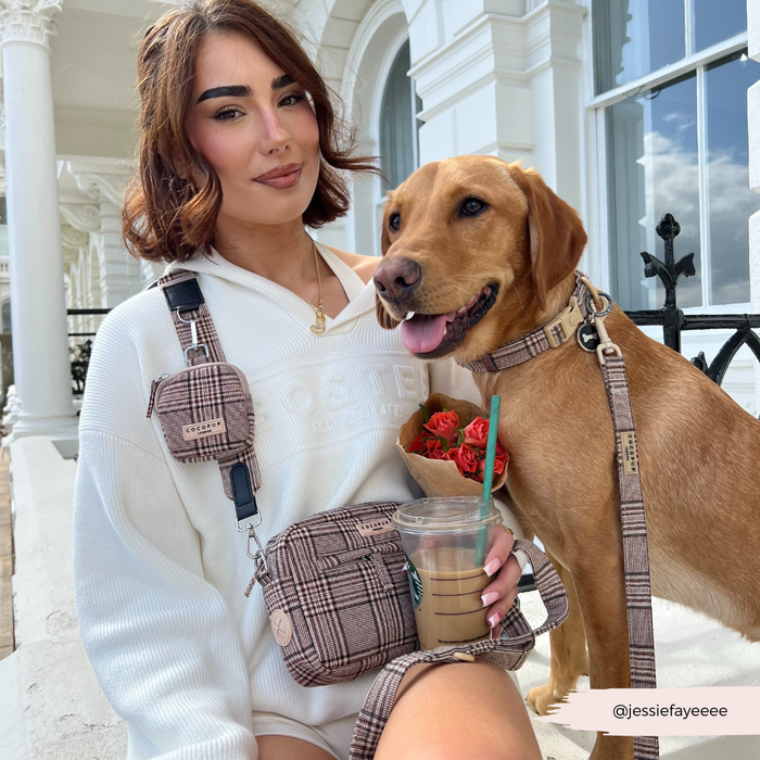 Woman and dog in matching plaid, holding a Cocopup London Pup Plaid dog walking bag with coffee and flowers.