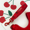 Red velvet dog lead with cherry print and subtle Cocopup London branding, shown with matching harness.