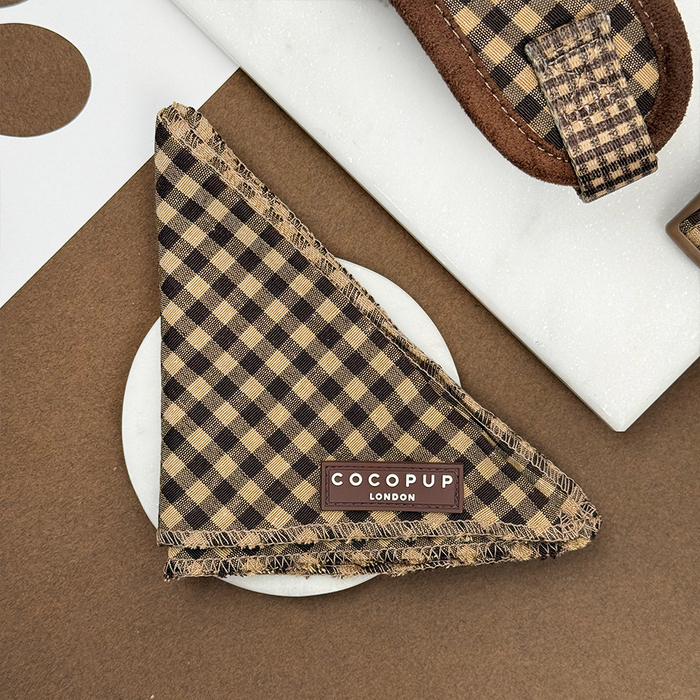 Brown and beige Cotswold Check Bandana by Cocopup London on a textured white and brown background.