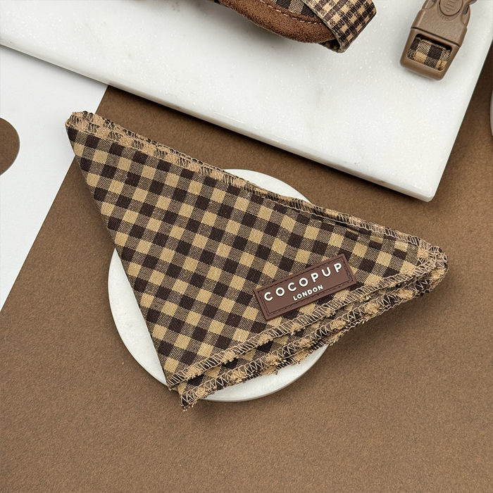 Brown and beige checkered dog bandana displayed on a white dish.