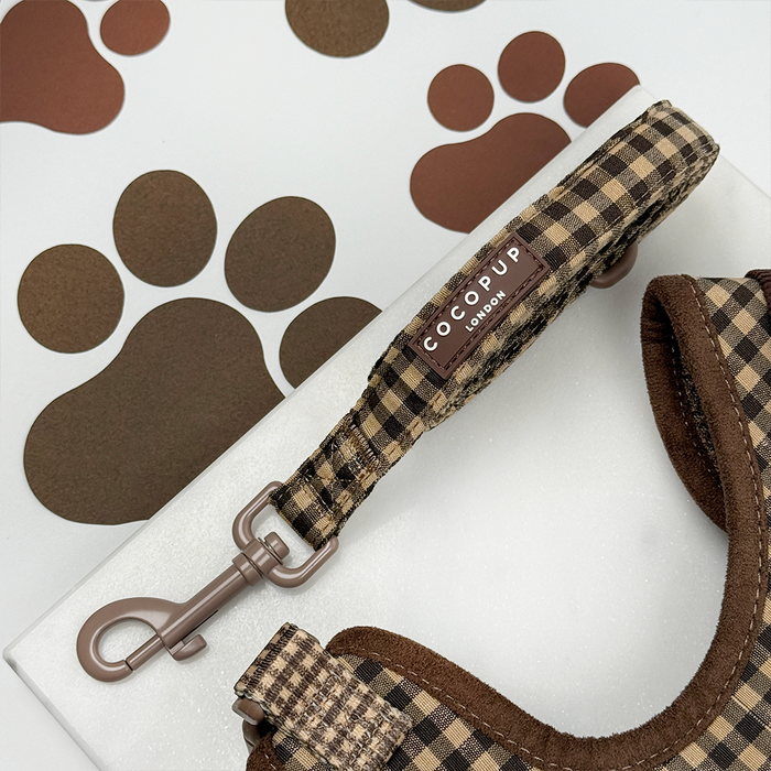 Brown check Cocopup London dog lead on a brown surface with paw prints.
