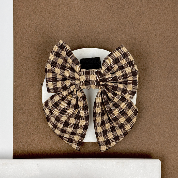 Cocopup London Cotswold Check Sailor Bow Tie hair clip on a white card, set against a brown background.