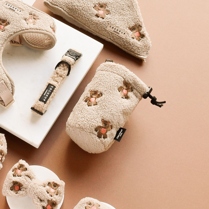 Beige fleece drawstring treat pouch with floral embroidery, shown on a tan background.