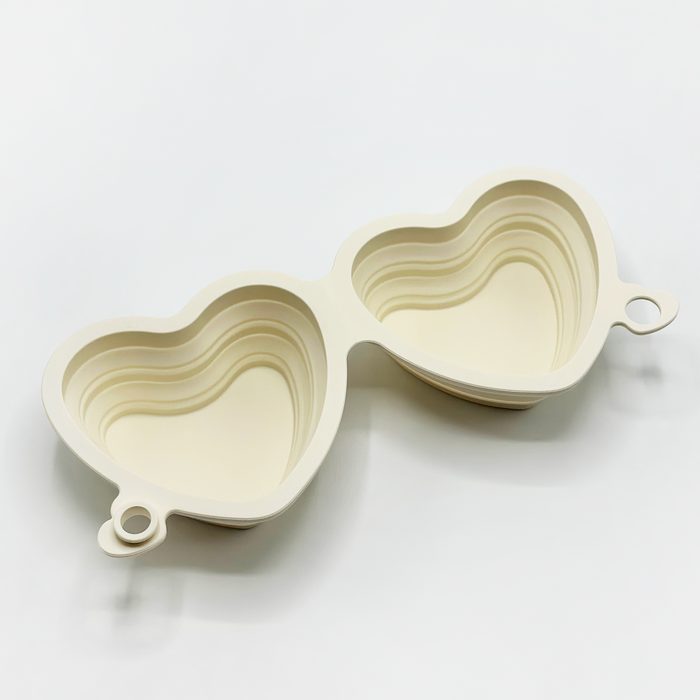 Cream heart-shaped collapsible bowl with two small handles, nested on a plain white background.