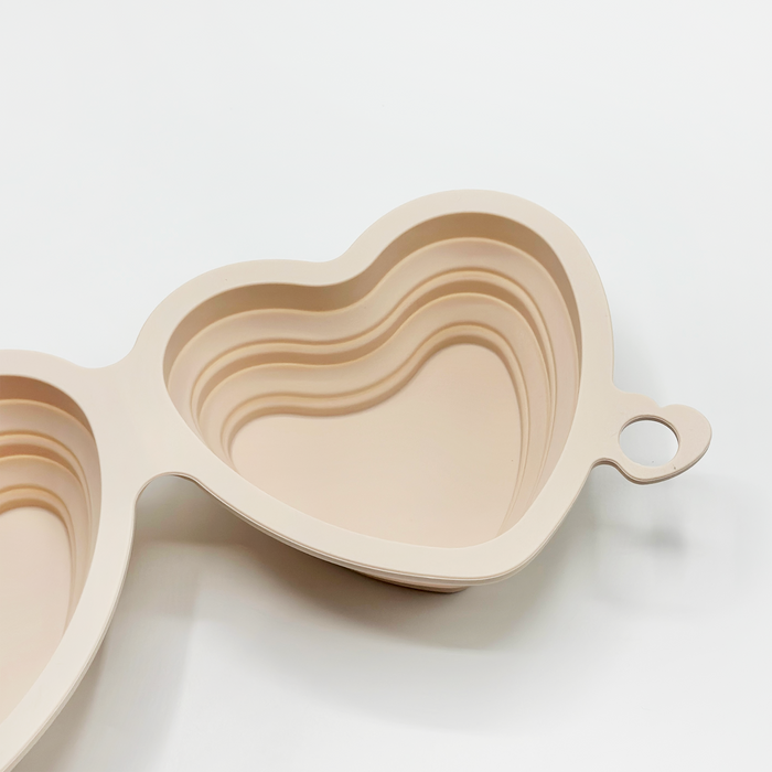 Pink silicone collapsible dog bowl with a heart design, compact and stackable for travel.