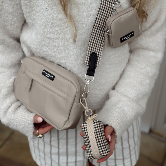Woman with a cream sweater, striped shorts, and a Cocopup London Heritage Check crossbody poop bag holder.