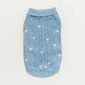 Light blue cable knit dog sweater featuring white heart pattern and a branded label on the front.