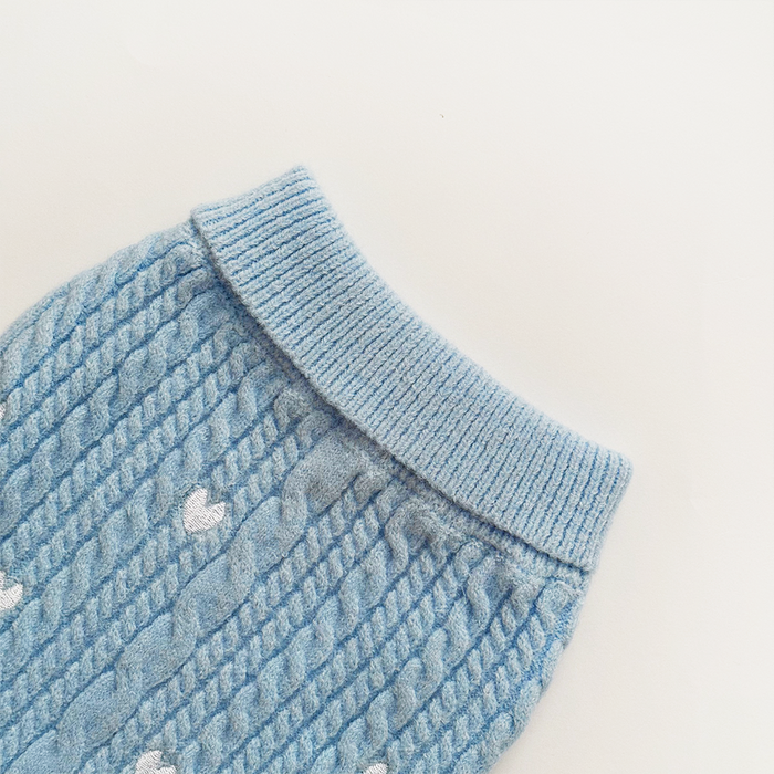 Light blue cable knit dog sweater with white heart pattern and ribbed collar.