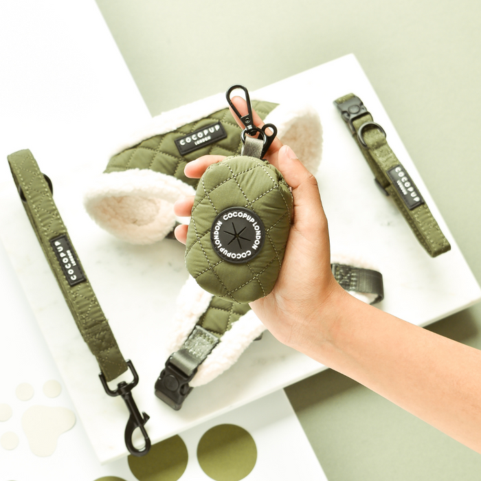Hand holding khaki quilted Cocopup London poop bag holder, with matching accessories on a white surface.