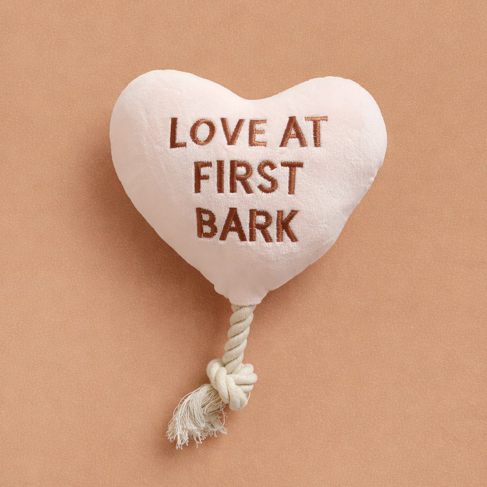 Red heart-shaped dog toy with Love at First Bark text and a knotted white rope tail from Cocopup London.