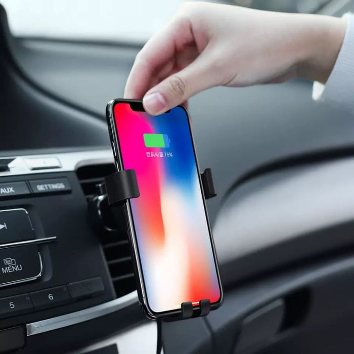 9eight5 phone holder and wireless charger attached to a desk, holding a smartphone with charging indicator visible.