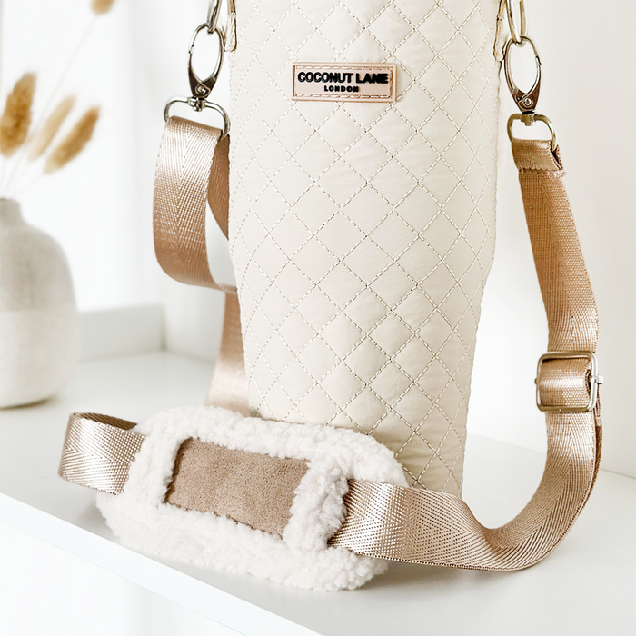 Cream quilted tumbler carry case with gold strap by Cocopup London, displayed on a white shelf.