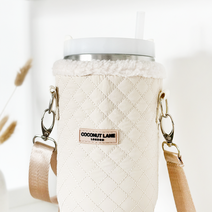 Cream quilted tumbler carry case by Cocopup London with adjustable strap, holding a cup with lid and straw.