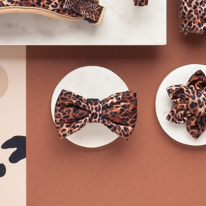 Quilted leopard print dog bow tie with Cocopup London tag displayed on white stands.