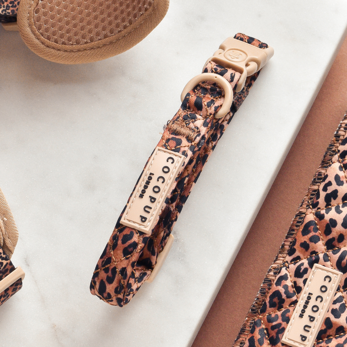 Quilted leopard print dog harness, lead, and collar set from Cocopup London on a marble surface.