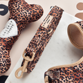 Quilted leopard-print dog lead, toy bone, and harness from Cocopup London on a marble and beige surface.