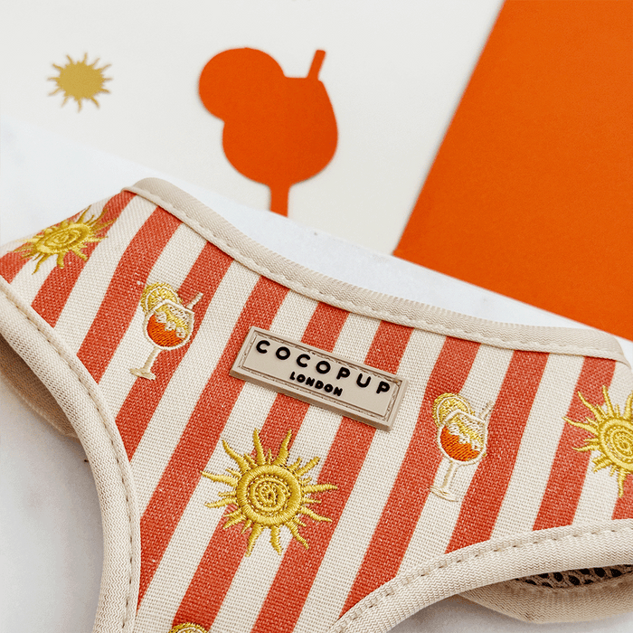 A orange and beige stripe dog harness, with embroidered drink and sun graphics.