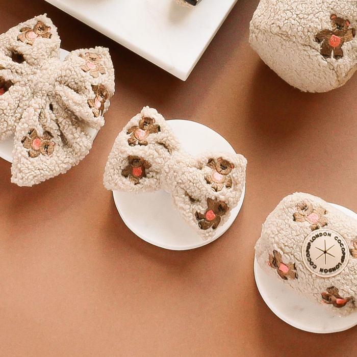 Theo Embroidered Teddy Bow Tie by Cocopup London, featuring floral embroidery, displayed on white platforms with a brown backdrop.