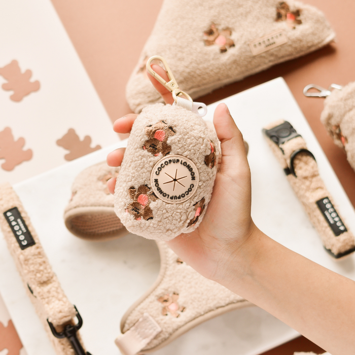 Cream teddy-print Cocopup London Theo Poop Bag Holder, held in hand, with embroidered details.