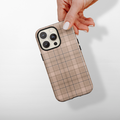 Hand holding a Cocopup London Pup Plaid tough phone case on an iPhone, shown against a plain light background.
