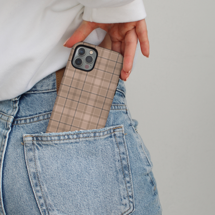 A hand slips a plaid Cocopup London phone case into the back pocket of light blue jeans.