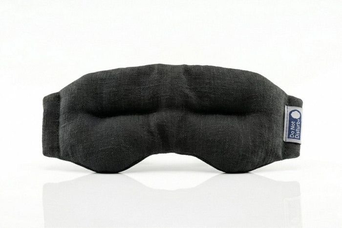 Black weighted eye mask by Do Not Disturb Sleep Company, designed for relaxation and sleep, with soft fabric and adjustable straps.